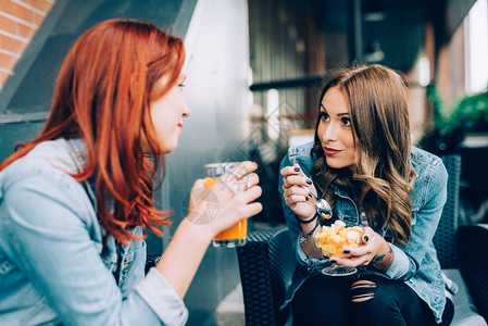 两个女孩坐在酒吧里喝着水果沙拉和果汁聊天最好的朋友图片
