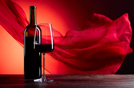 中红底素材红底玻璃和一瓶红葡萄酒红色的细布在风中飘背景