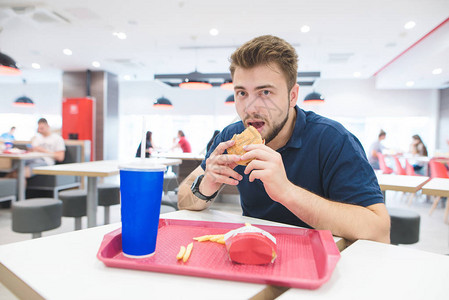 留着胡子的男人坐在快餐店的桌子旁图片