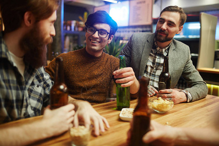 快乐的年轻男人喝着饮料坐在餐桌图片