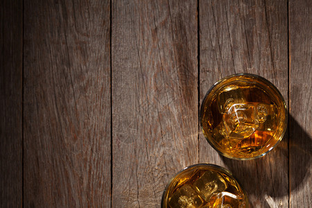 玻璃杯威士忌和木制桌上的冰块顶视图片