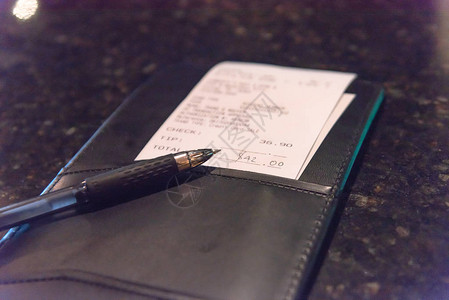 打开带有餐厅账单和笔的皮革支票夹图片