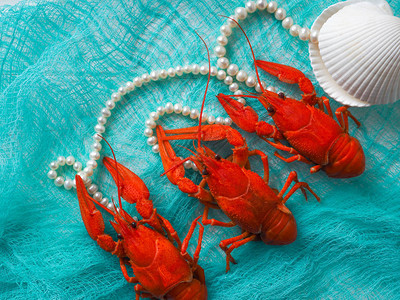 三条红煮的龙虾躺在蓝布上图片