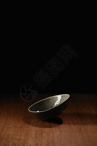 空陶瓷碗飞过木桌表面图片