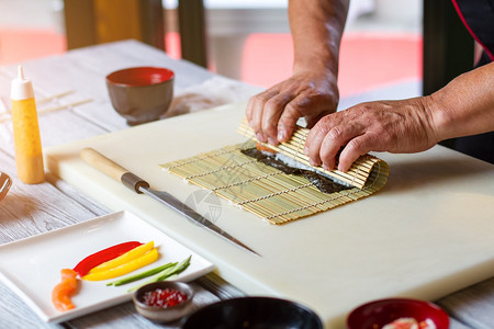 人手摸竹垫刀子躺在竹垫附近餐厅厨房的寿司厨师图片