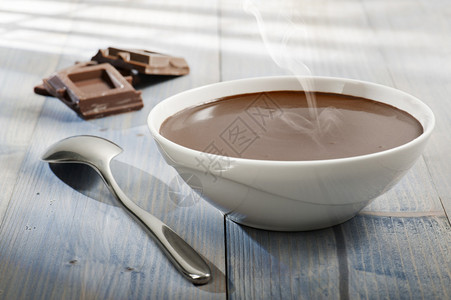一杯热融化的巧克力加勺子和巧克力块图片