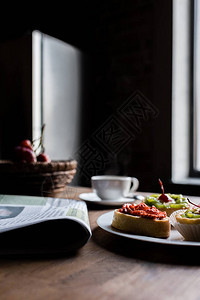 报纸早餐蛋糕和热咖啡在窗前的桌图片