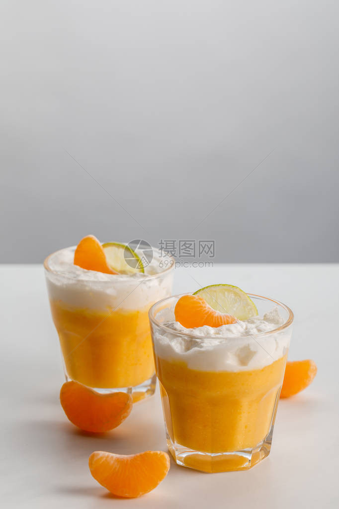 两杯橙慕斯配橘子和酸橙片图片