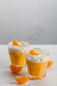 两杯橙慕斯配橘子和酸橙片图片
