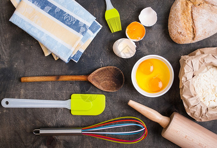 用餐具餐巾纸蛋壳面包面粉擀面杖烘烤深色背景从上面的老式木桌图片