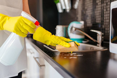妇女用海绵和喷雾清洁剂清洗厨房柜子图片