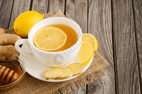 质朴的木桌上加柠檬姜和蜂蜜的甘菊茶图片