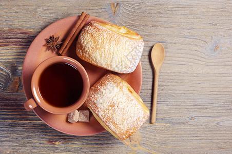 两块新鲜面包和一杯热茶放在生锈的木制桌子图片