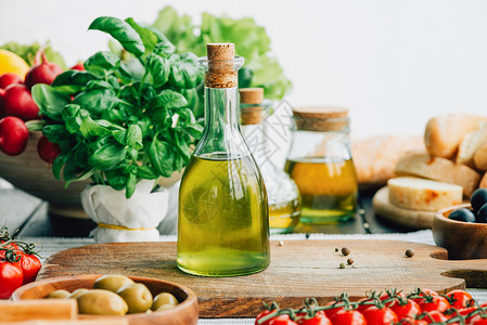 木桌上有蔬菜的橄榄油瓶图片