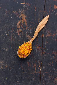 用木勺在破旧的黑色桌子上干黄花瓣菊芋烹饪健康饮料的成分乡村草图片