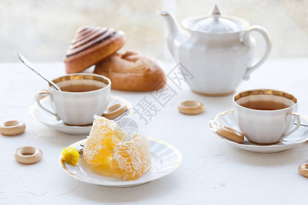 一杯加蜂蜜的茶盘子上还有茶壶图片