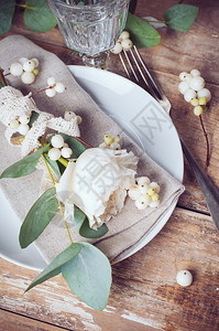 配有花装饰餐巾纸白玫瑰树叶和木板背景的图片