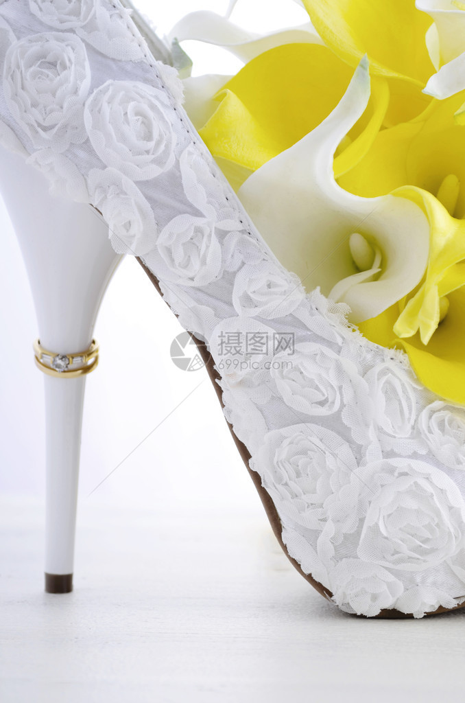 结婚日概念与戒指相伴的脚跟美丽的白色花岗的新娘短裙鞋和花束在白图片