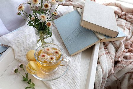 桌上托盘里的茶书菊花和马卡龙舒适的理念图片