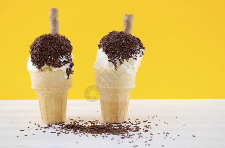 儿童节快乐概念与有趣的冰淇淋锥巧克力喷洒在白色破旧的玉米饼背景图片