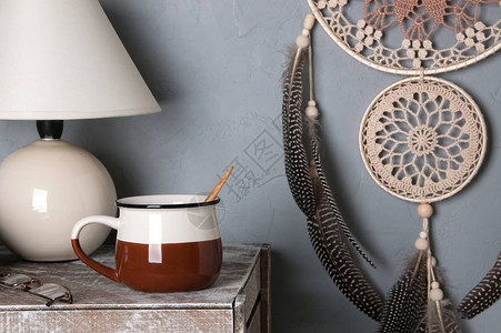 褐色编织机在灰色背景的卧室内部做梦捕捉器杯子和桌灯图片