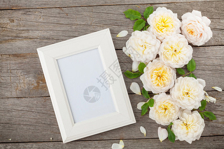 空白相框和白玫瑰在木桌背景图片