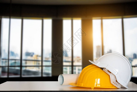 建筑房屋和建筑修理工程建筑图纸和白桌上的头盔图片