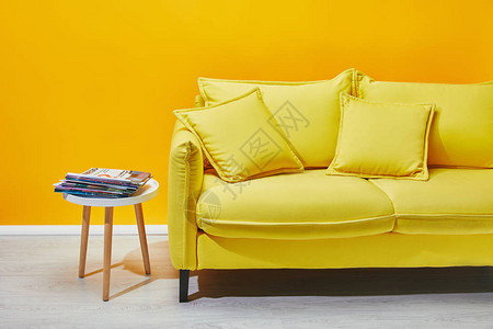沙发上铺有枕头和咖啡桌在黄背景图片
