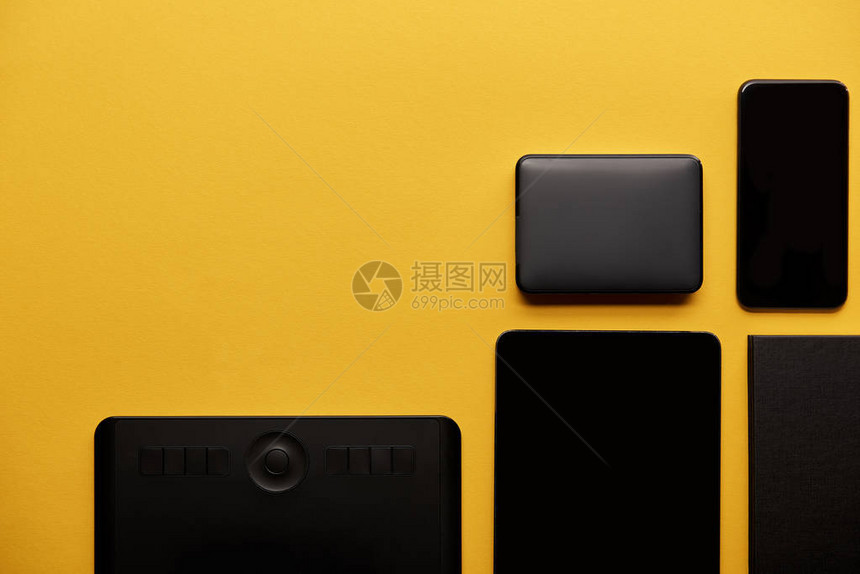 黄色表面带有数字平板智能手机和便携式hdd图片
