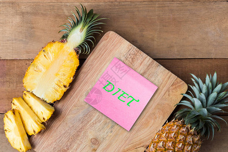 木切割板上的菠萝切片用纸条上的食物文字背景图片