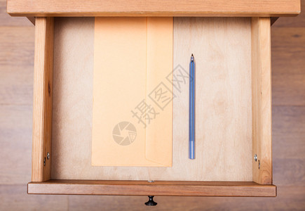 床头柜打开抽屉中蓝色笔和信封的顶部视图图片