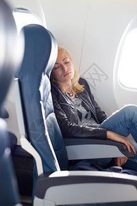 疲倦的金发美女随便的caucasian女士在坐着不舒适的座位上睡觉图片
