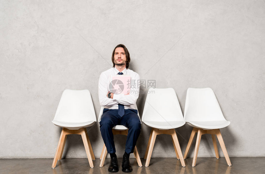 英俊男子坐在椅子上手持横跨双臂图片