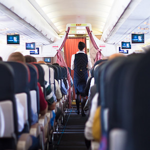 机上坐着乘客和乘务员在过道行走背景图片