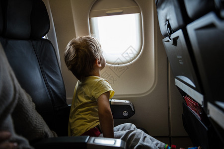 小男孩在飞机上望着窗外背景图片