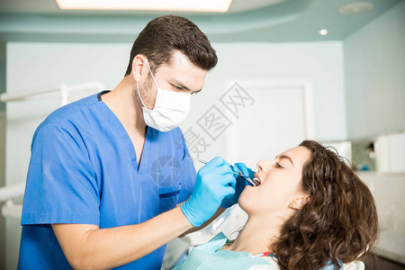 接受男牙医在诊所牙科治疗的女图片