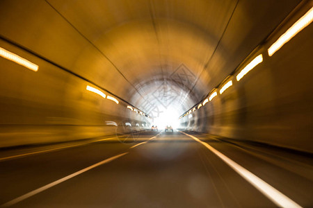 汽车在灯光照亮的隧道中高速行驶图片