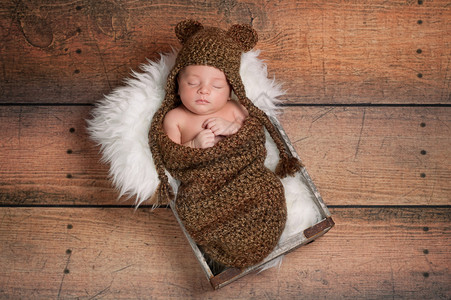 三周前刚出生的男婴戴棕色编毛帽高清图片