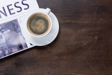 木桌上咖啡杯和报纸的特写俯视图图片