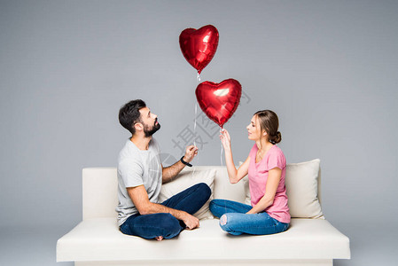 坐在白沙发上的一对夫妇与红色心形气球图片