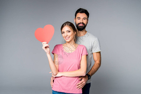 带着红纸心脏的年轻夫妇在背景图片