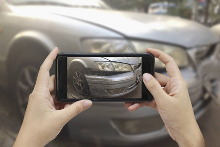 手拿着智能手机在车祸现场拍照车祸保险图片