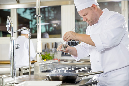厨师和他的助手在专业厨房的美食餐厅或酒店做牛肉排菜图片