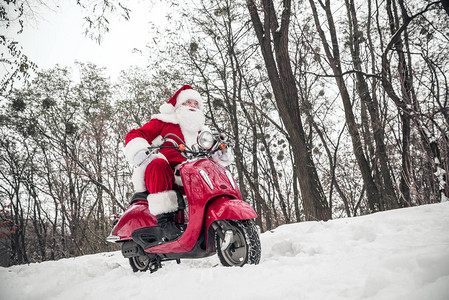 在冬季公园骑着红色摩托车的圣诞老图片