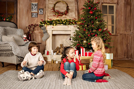 在壁炉附近带着圣诞礼物坐在地毯上玩背景图片