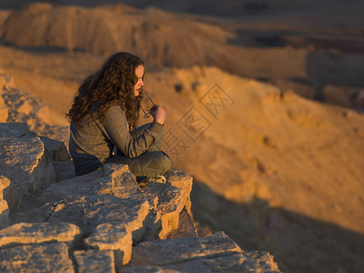 以色列内盖夫沙漠马赫特什拉蒙沙漠中坐在岩石图片