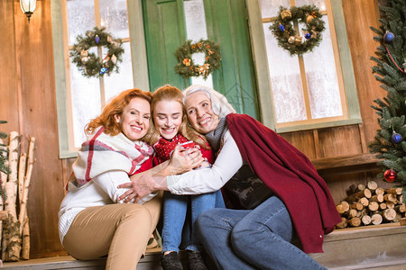 三代人的家庭快乐坐在楼梯上拥抱喝热茶的欢乐家庭图片