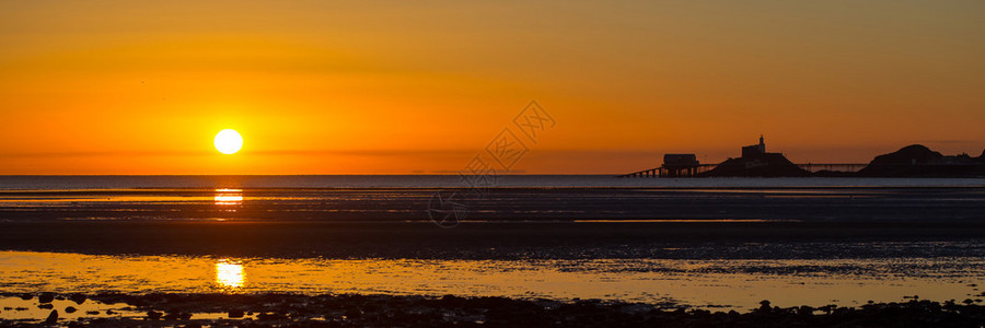 太阳升起在天鹅海湾大片的泥滩上图片