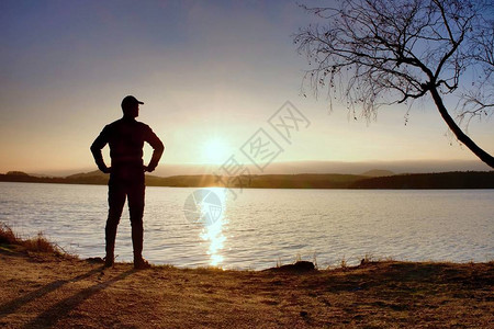 孤单的运动员看着秋湖岸上多彩的日落图片