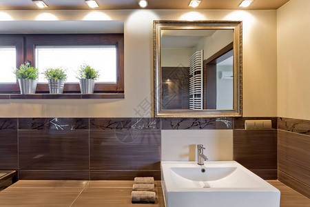 棕色浴室有大瓷砖和古老的镜子图片